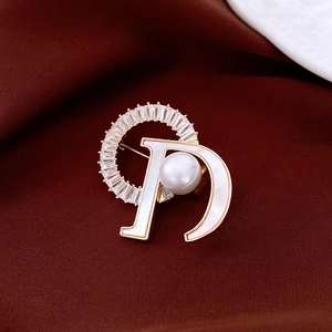Detailed macro view of 18k gold plated letter D brooch with pearl and crystal inlay