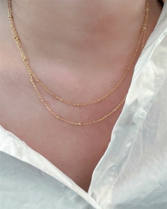 Double-layered gold-plated stainless steel necklace displayed on a model's neck