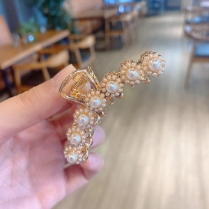Detail of elegant gold claw clip featuring white faux pearls in floral pattern