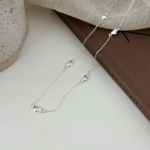 Detail of silver heart necklace with five solid pendants on a minimalist chain