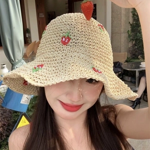Detail of hand-woven beige straw hat with delicate red strawberry embroidery patterns