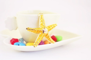 Detailed macro view of a yellow starfish keychain charm hanging on a white porcelain cup