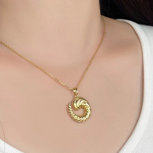 Detail of a golden twisted croissant pendant necklace on model with vintage style