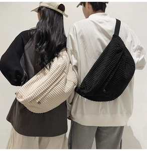 Detail of minimalist corduroy crossbody bags in beige and black worn by male and female models