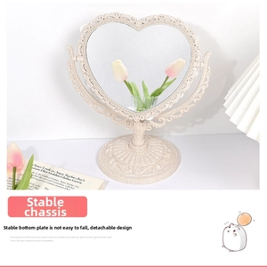 Detail of vintage heart-shaped makeup mirror with embossed frame and stable base