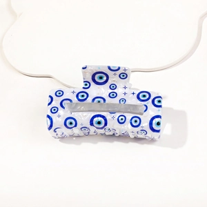 Close-up of pearl white acetate hair claw clip featuring blue evil eye and star patterns