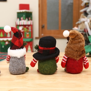 Three Christmas gnomes with plaid hats and reindeer antlers on a wooden table