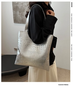 Detail of metallic silver tote bag with crocodile pattern texture shown on a shoulder
