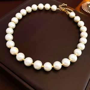 Detail of baroque pearl necklace with gold spacer beads on dark leather surface