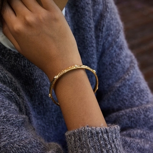 Detailed view of gold hammered texture bangle with clear zircon stones on a model wrist