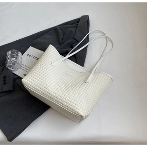 Detailed top view of a white woven tote bag on a blazer for office fashion styling