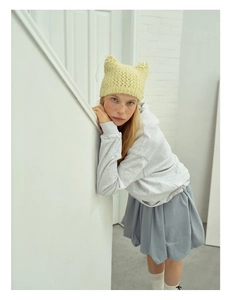 Detail showing hand-knitted yellow cat-ear beanie with cute bow and hollow design