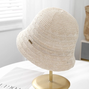 Detailed view of a breathable ivory knitted bucket hat with gold metal label decoration