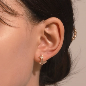 Close-up of a gold butterfly earring with sparkling zircon inlay worn by a model