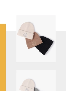 Detail showing various colors of knitted beanies with embroidered smiley face patches