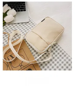 Macro view of beige nylon crossbody bag with zip pocket and adjustable fabric strap