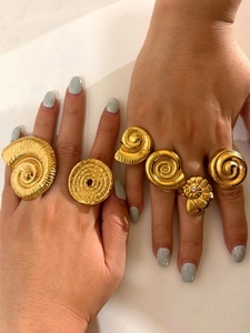 Detail view of 6-piece golden seashell and conch open rings on hands in lifestyle setting