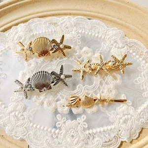Elegant gold and silver starfish hair clips with pearls and rhinestones on white lace
