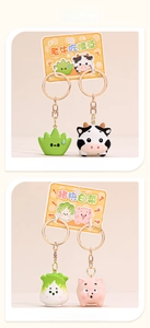 Close-up of cute cartoon pig and cow couple keychains with gold lobster clasps
