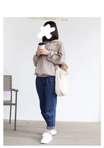 Detailed shot of a beige canvas tote bag paired with a casual pink hoodie and denim jeans