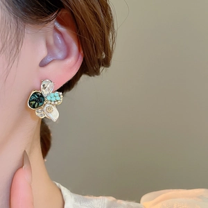 Gros plan de boucles d'oreilles fleurs en perles et strass sur l'oreille d'un mannequin