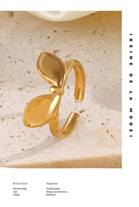 Detailed view of an adjustable gold bow ring on a textured stone and silk background