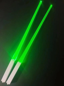 Close-up of dual green LED glowing light-up chopsticks with white plastic handles