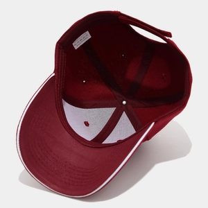 Detail view of burgundy baseball cap interior with white wash label and polyester tag