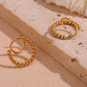 Macro detail of 18K gold plated stainless steel twisted rope hoop earrings on stone