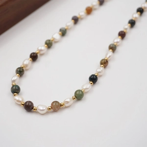 Colorful gemstone and freshwater pearl necklace with gold spacer beads on white background