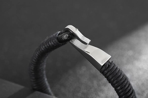Close-up of black braided leather bracelet with a silver stainless steel hook clasp