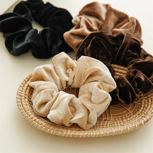 Set di grandi elastici scrunchie in velluto dai toni caldi su un vassoio intrecciato