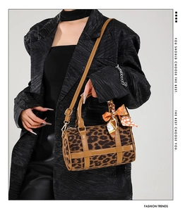 Detail of leopard print Boston bag with brown leather trim and orange floral silk scarf