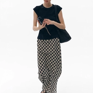 Detail of slim-fit black cap sleeve t-shirt paired with yellow plaid maxi skirt