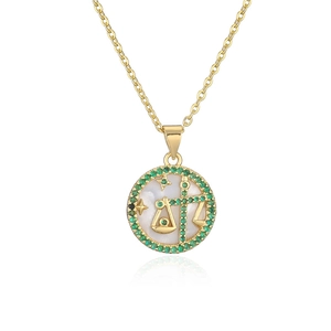 Macro detail of Libra zodiac pendant with white shell base and green gemstone border