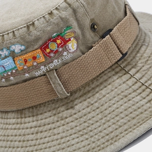 Detailed embroidery of a colorful train and Happy Smile Kids text on a khaki sun hat