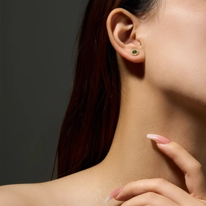 Detail of 925 silver stud earring with green gemstone worn by a model in soft light