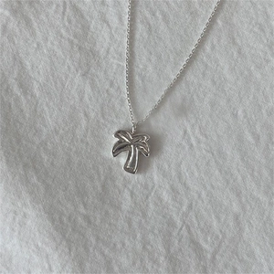 Minimalist 925 sterling silver palm tree pendant necklace on white textured fabric