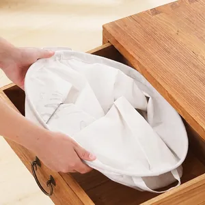 Foldable cotton linen laundry basket in cream white being placed into a wooden drawer