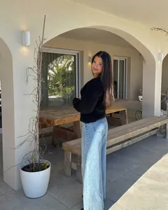 Close-up of a long-sleeved black knit sweater paired with light blue high-waist jeans