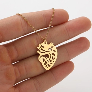 Golden anatomical heart pendant necklace in stainless steel resting on a hand