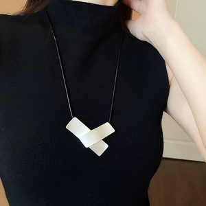 Detail of a minimalist geometric pendant necklace with white rectangular resin plates