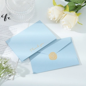 Detailed view of blue paper envelopes with gold Thank You text and wax seal stamp