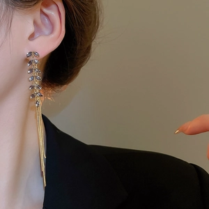 Detail of long tassel earrings with gold leaf pattern and dark grey crystal stones