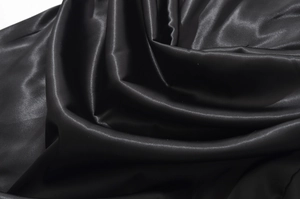 Détail du tissu en satin noir montrant une texture luxueuse et un éclat soyeux doux