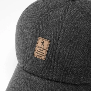 Macro view of thick dark gray fabric texture and leather logo patch on warm baseball cap