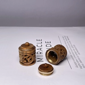 Detailed view of hand-carved sandalwood sachet pendant with brass accents and hollow design