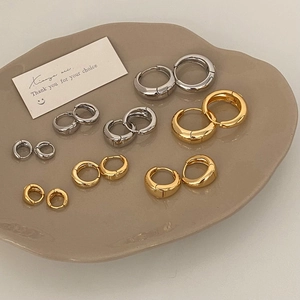 Detailed view of minimalist gold and silver hoop earrings in various sizes on a tray