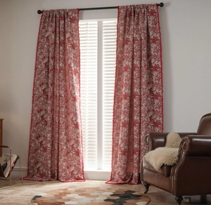 Detail of red palm leaf pattern curtain with decorative red pom-poms on the edge