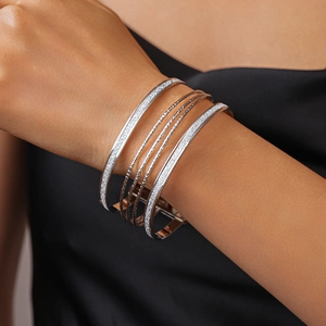 Macro detail of layered geometric metallic bracelets with matte and glitter textures